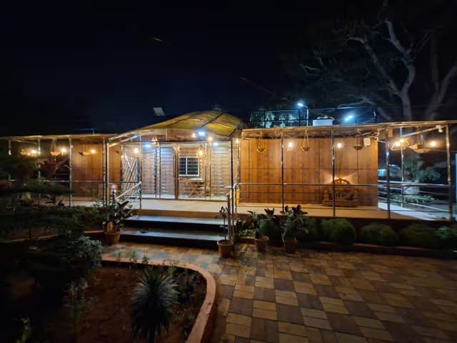 Aamaghara container homestay warmly lit at night amid trees